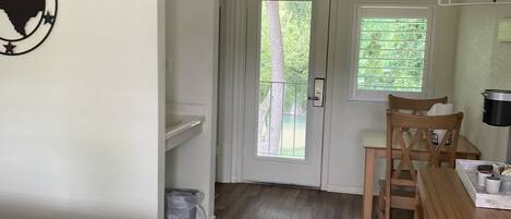 Une pièce comprenant un lit, un bureau en bois, une chaise, une porte donnant sur l’extérieur et un mur orné d’une pancarte de bienvenue.