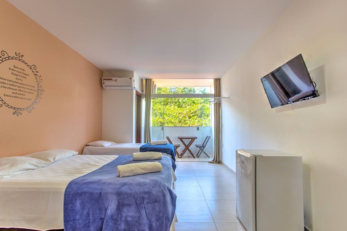 Habitación de hotel con dos camas, un televisor y un balcón con mesa y sillas.