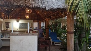 A cozy outdoor seating area with a thatched roof, string lights, and a chalkboard menu. - Hotel Quinta Diamante - Barra vieja  (Acapulco)