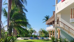 A resort with a well-maintained lawn, palm trees, and a thatched-roof building with a staircase leading to the upper level. - Hotel Quinta Diamante - Barra vieja  (Acapulco)