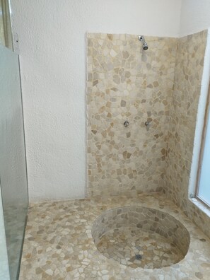 A shower with mosaic tile walls and floor, a circular drain, and a window on the right. - Hotel Quinta Diamante - Barra vieja  (Acapulco)