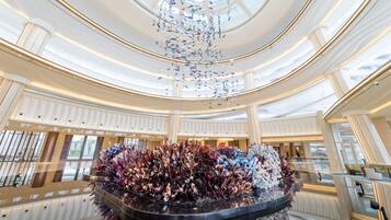 A spacious, multi-level atrium with a central decorative fountain and a modern chandelier.