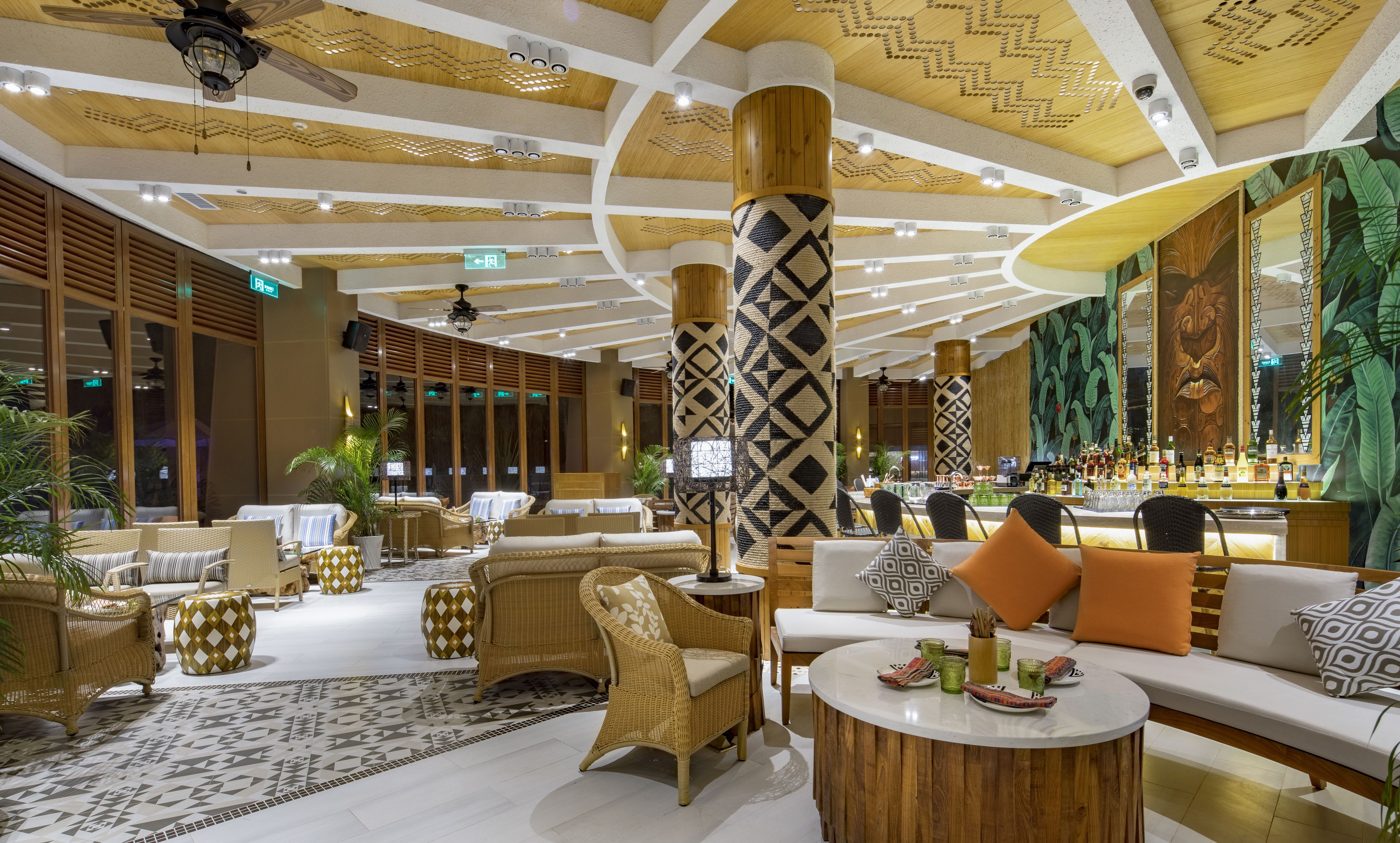 A spacious lobby with wicker furniture, a bar area, and a patterned floor.