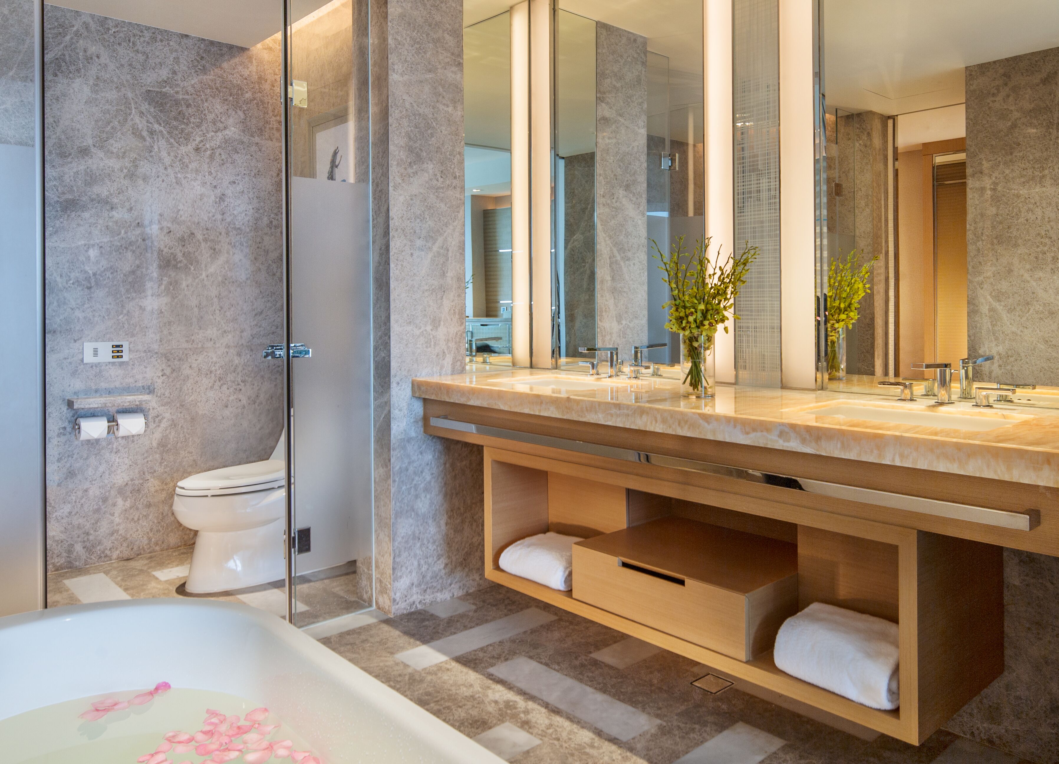 A modern bathroom with a large mirror, a bathtub, and a shower area.