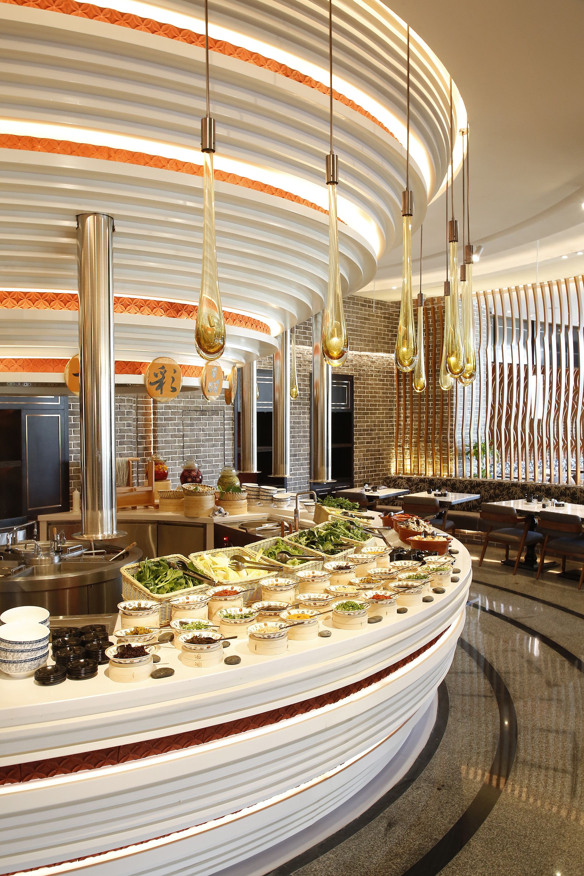 Un espace repas moderne avec un buffet, comprenant un comptoir blanc incurvé où sont présentés les plats, et un mur en briques en arrière-plan.