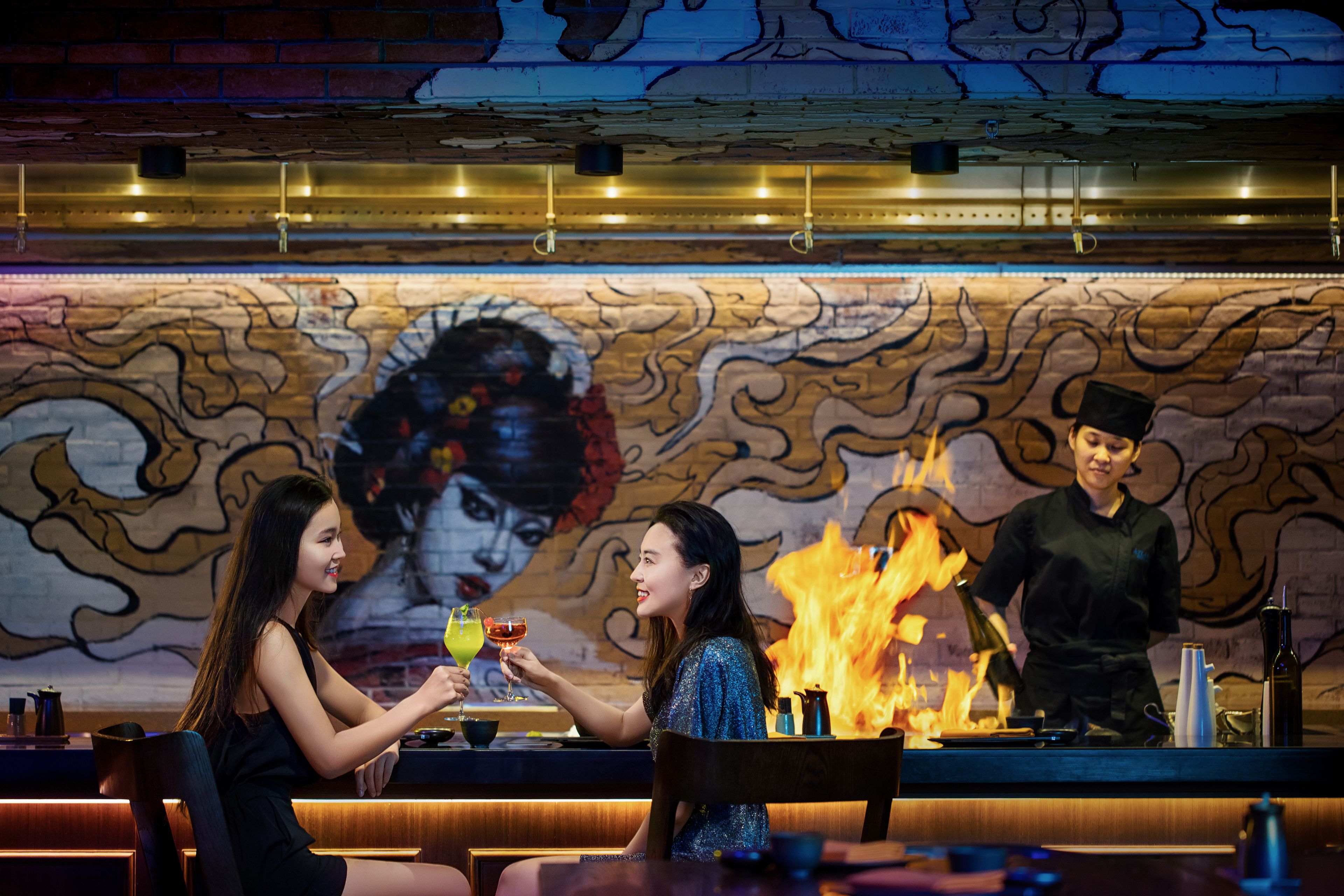 Eine Bar mit Wandmalerei, Feuerstelle und Barkeeper.