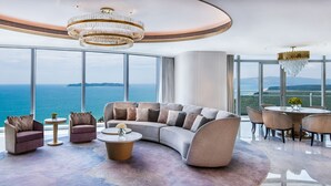 A modern living room with a curved sofa, a TV, and a dining area with a table and chairs. - Atlantis Sanya (Sanya)