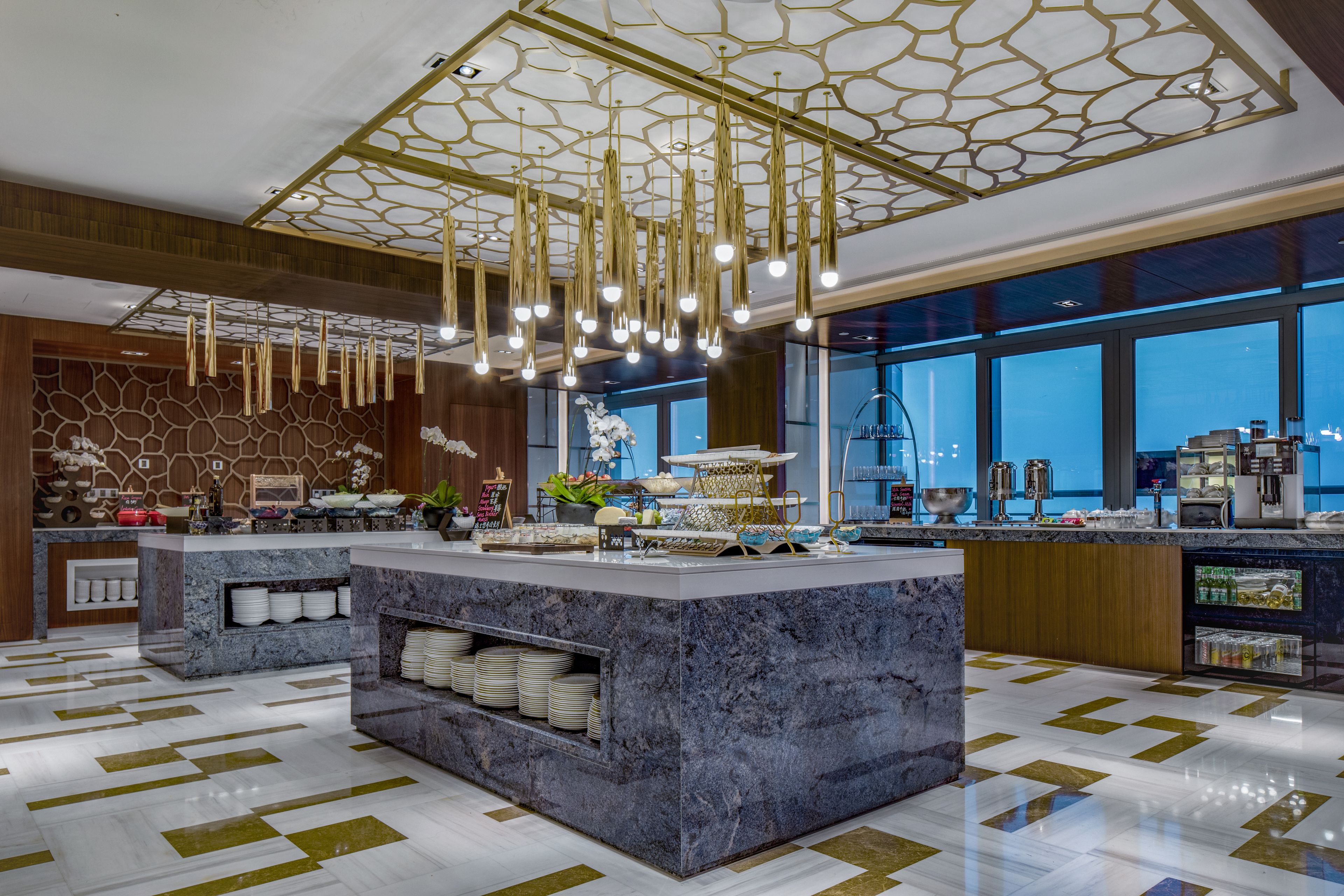 A modern kitchen with marble countertops, hanging lights, and a large island with a sink.