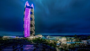 A tall, modern hotel with a distinctive purple-lit facade, surrounded by a landscaped area and a parking lot. - Atlantis Sanya (Sanya)