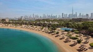 Ein Strandhotel mit Liegestühlen, einem Pool und Blick auf die Skyline der Stadt.