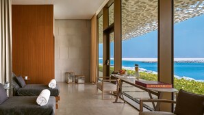 Ein modernes Hotelzimmer mit zwei Betten, einer Essecke und Blick aufs Meer.