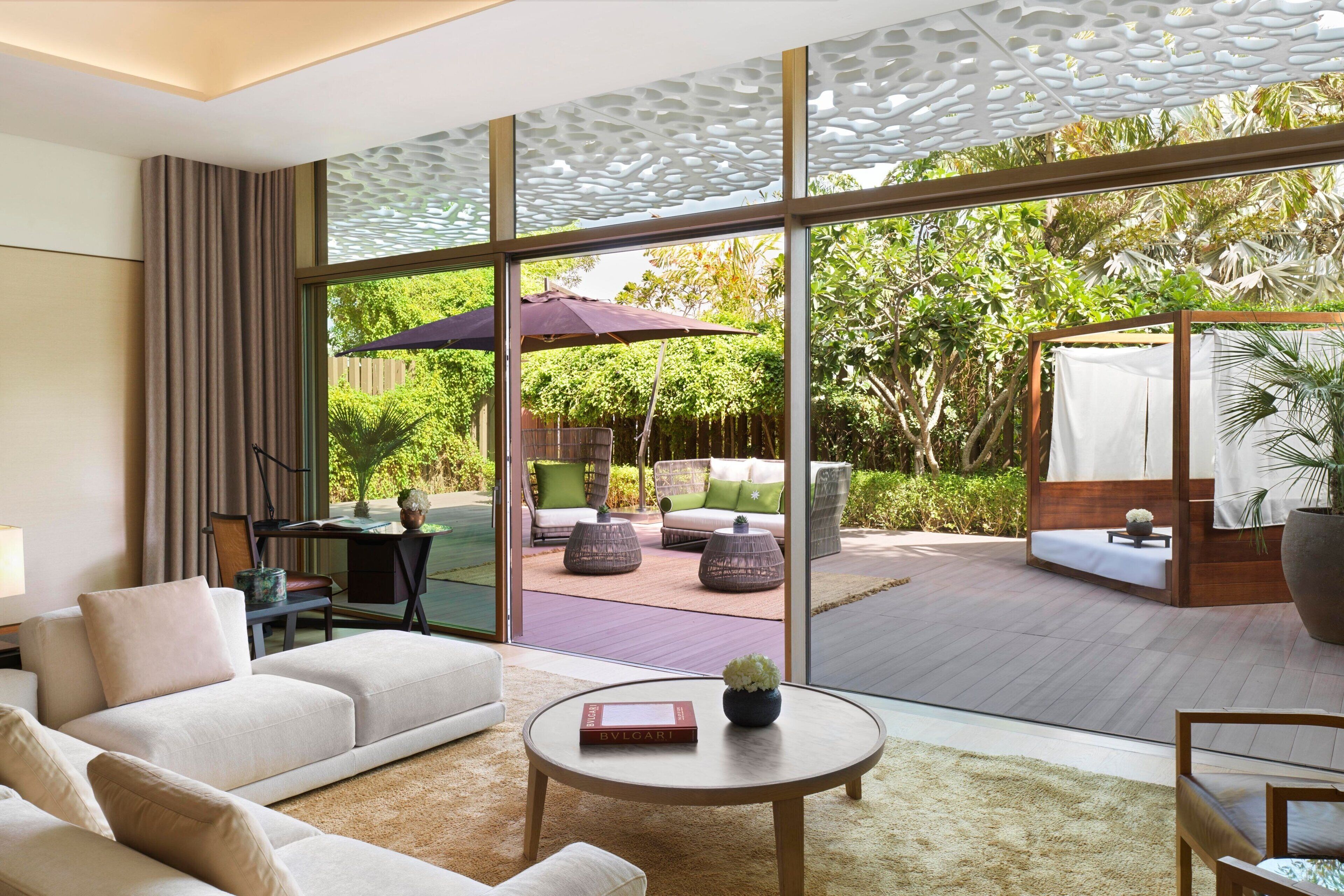 A modern living room with a large glass door leading to an outdoor patio area.