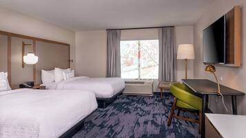 Une chambre d’hôtel avec deux lits, un bureau, une chaise, une télévision et une fenêtre avec des rideaux.