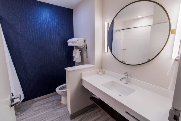 A modern bathroom with a white sink, a large mirror, and a toilet.