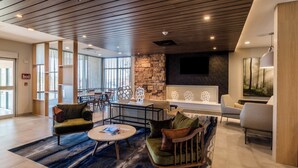A modern lobby with a stone accent wall, a seating area with sofas and a coffee table, and a large window providing natural light. - Fairfield Inn & Suites by Marriott Brownsville North (Brownsville)