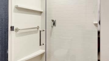 A modern shower area with glass doors, white tiled walls, and a built-in showerhead.