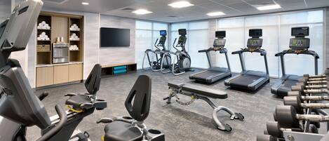 A gym with various exercise equipment, including treadmills, elliptical machines, and dumbbells.