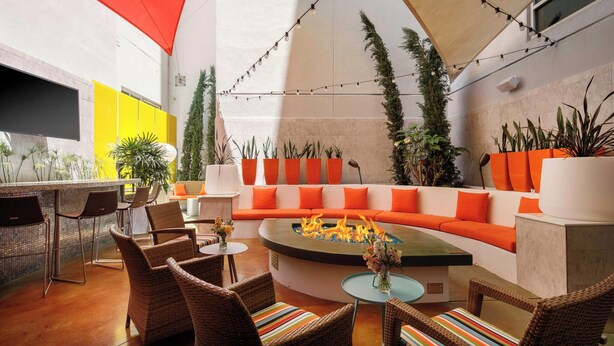 Un espace extérieur moderne aménagé avec des chaises en osier, une table ronde et un foyer.
