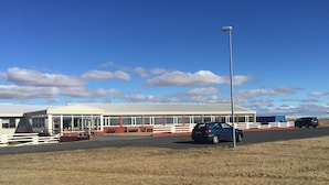 A building with a long, covered walkway and a fenced area in front.