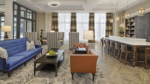 Amplia sala de estar con un sofá azul, un sillón marrón, una mesa de centro y una zona de bar con taburetes.