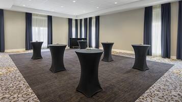 A conference room with a large table, four smaller tables, and a flat-screen TV.