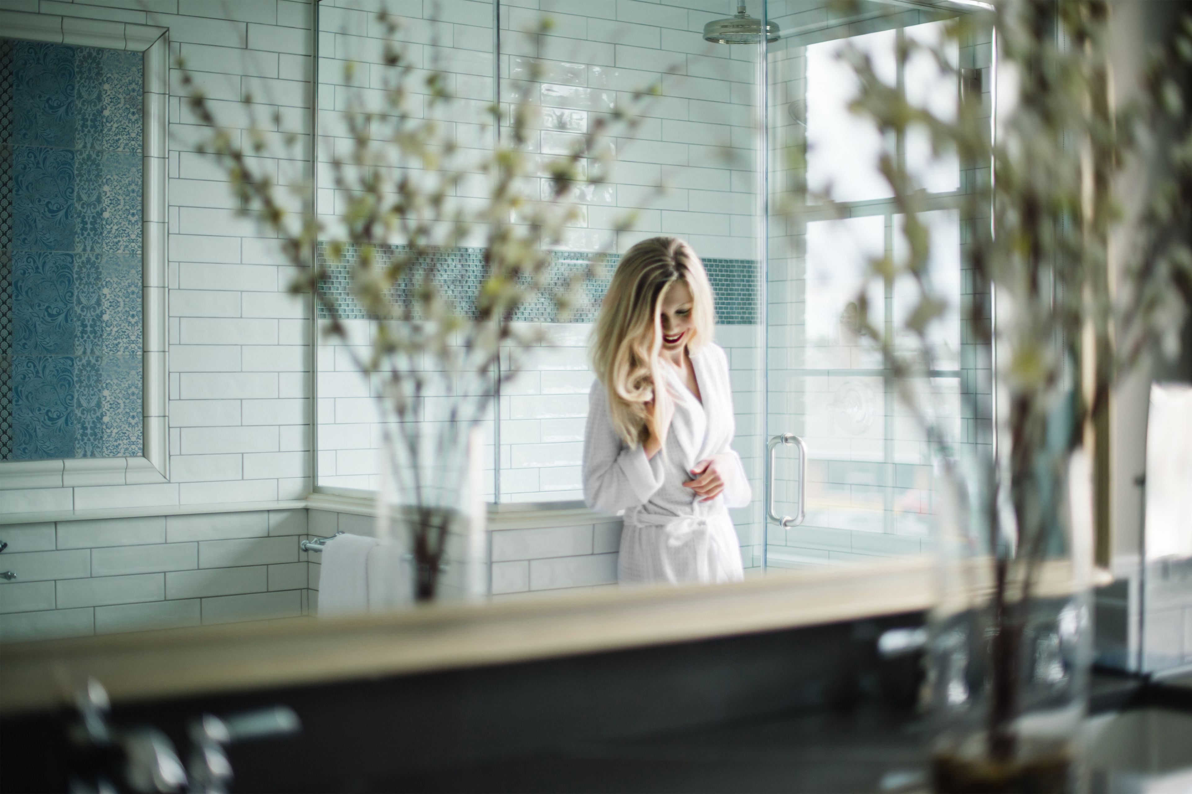 Une salle de bain avec un grand miroir, des carreaux blancs et une fenêtre.