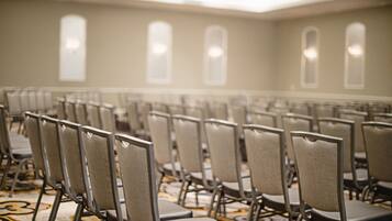 Rows of chairs in a conference room with a patterned carpet and a high ceiling with skylights.