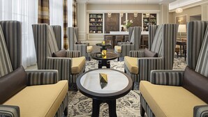 Un amplio salón con sillones y sofás a rayas, una mesa de centro y una estantería al fondo.
