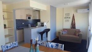 A compact living space with a kitchenette, a dining area with a table and chairs, a sofa, and a decorative wall with text.