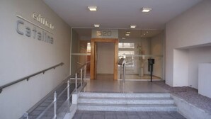 A modern building entrance with a glass door, a staircase leading to the upper floor, and a sign indicating the building name 'edificio Catalina'.