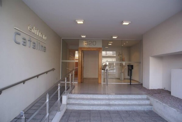 A modern building entrance with a glass door, a staircase leading to the upper floor, and a sign indicating the building name 'edificio Catalina'.