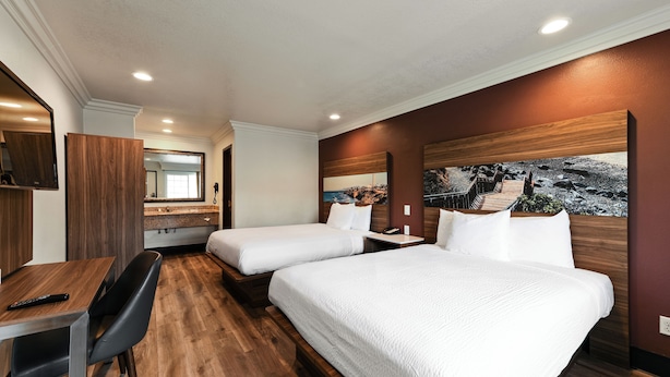 A hotel room with two beds, a desk, and a chair.