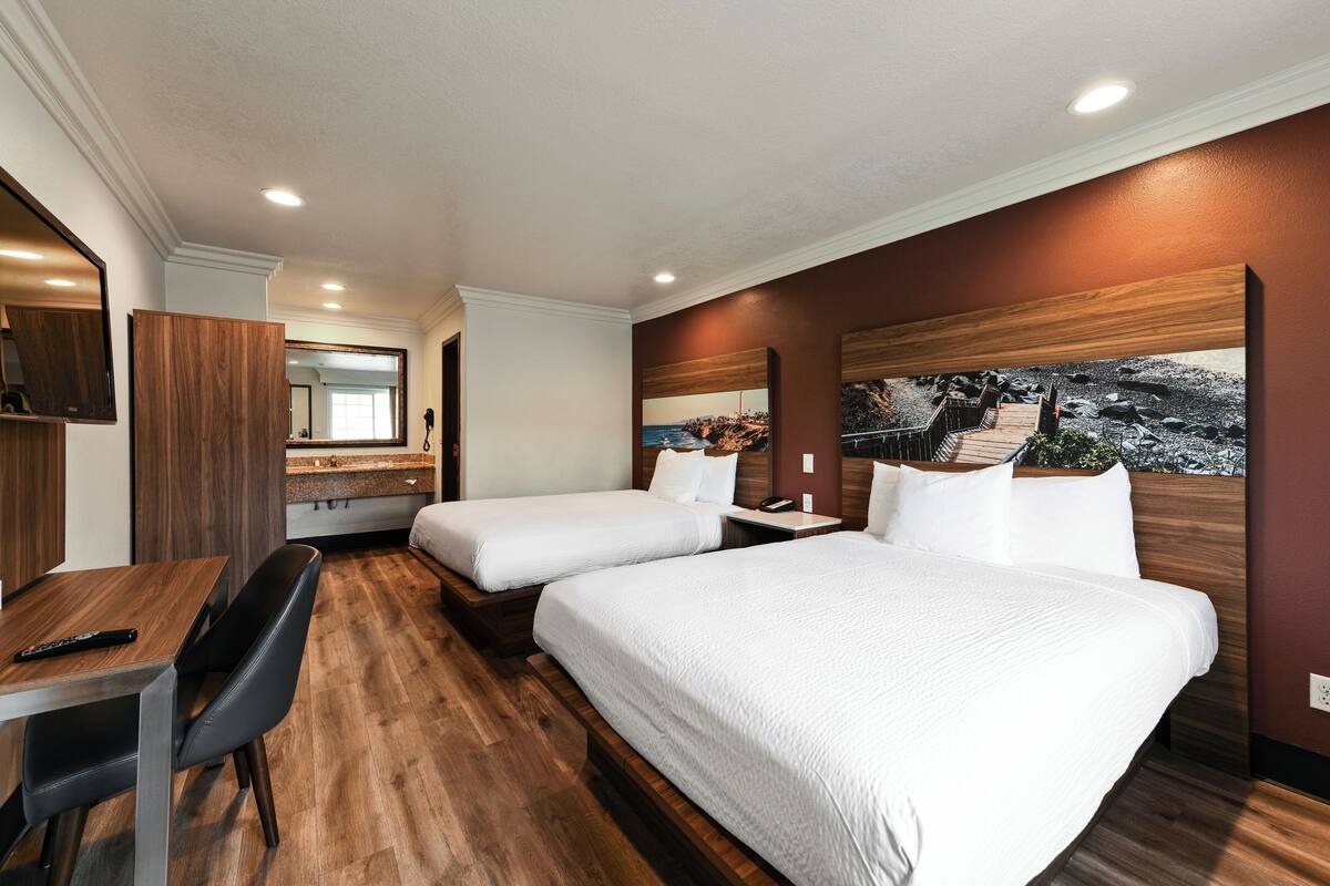 Une chambre d’hôtel avec deux lits, un bureau et une chaise.