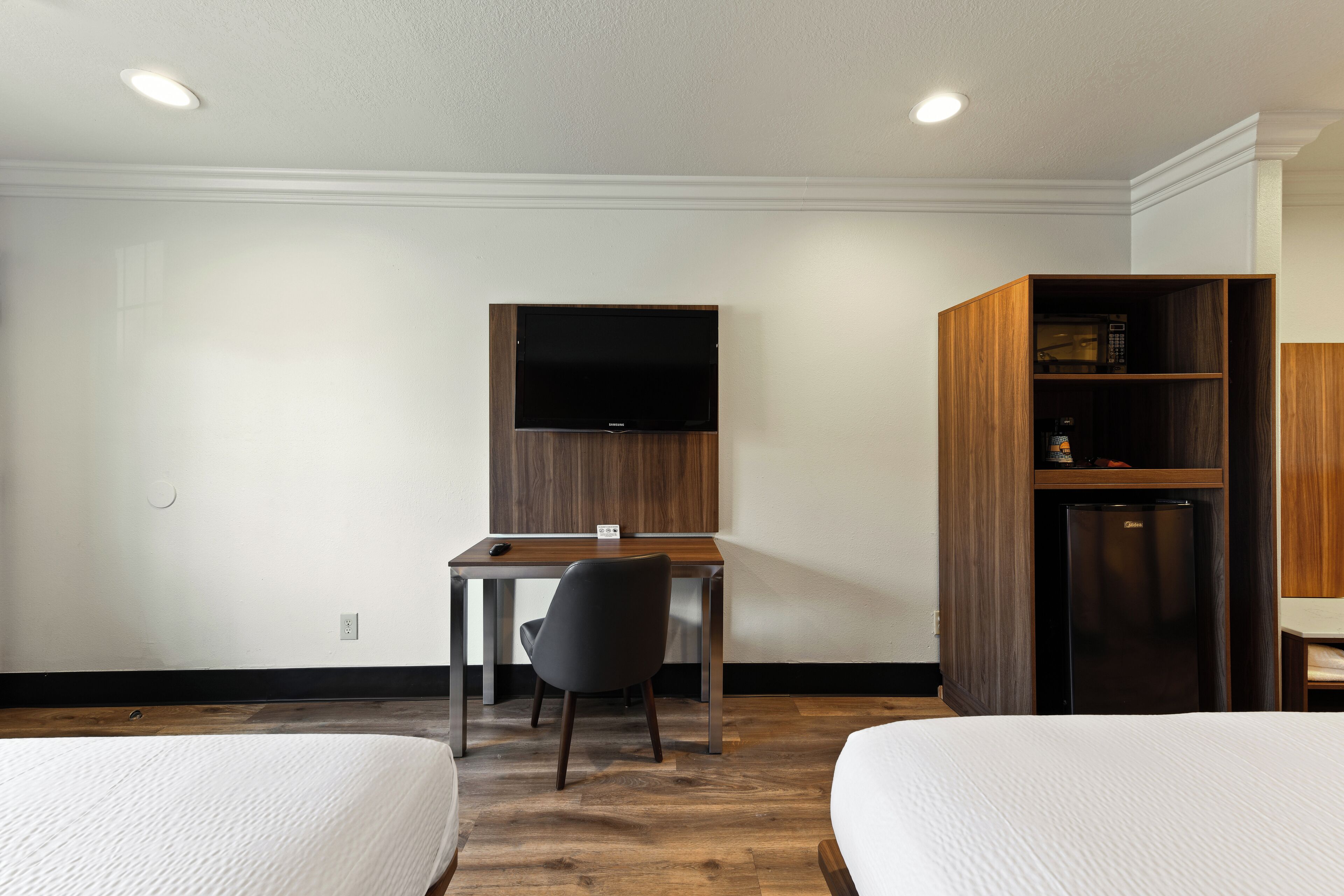 Une chambre d’hôtel comprenant un lit, un bureau avec une chaise, une télévision et un minibar.