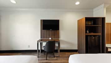 Une chambre d’hôtel comprenant un lit, un bureau avec une chaise, une télévision et un minibar.