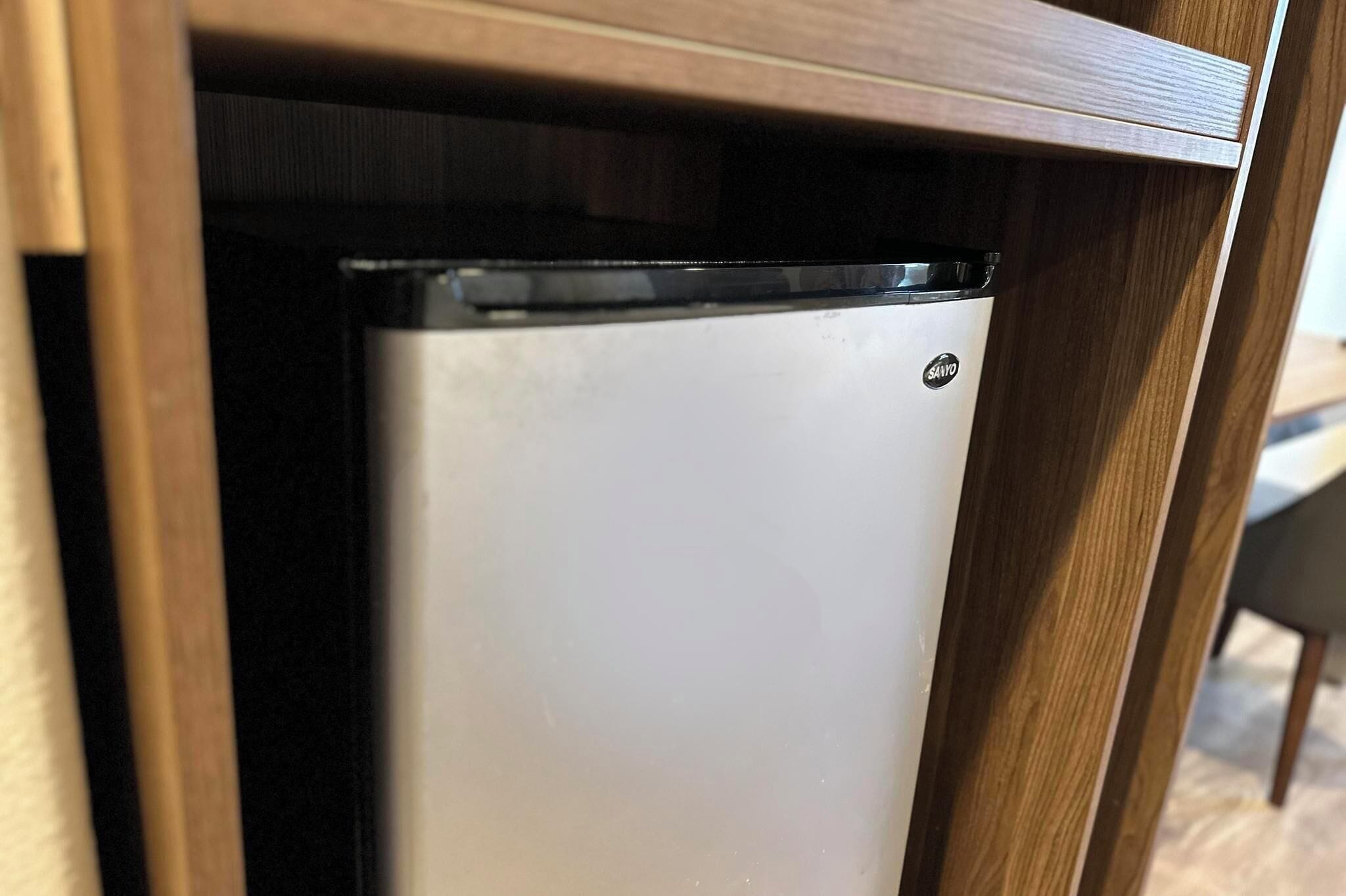 Un petit réfrigérateur blanc, doté d’un dessus noir, placé sous un meuble en bois dans une cuisine.