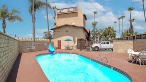 A swimming pool with a blue border, a Hyland Inn sign, and palm trees in the background.