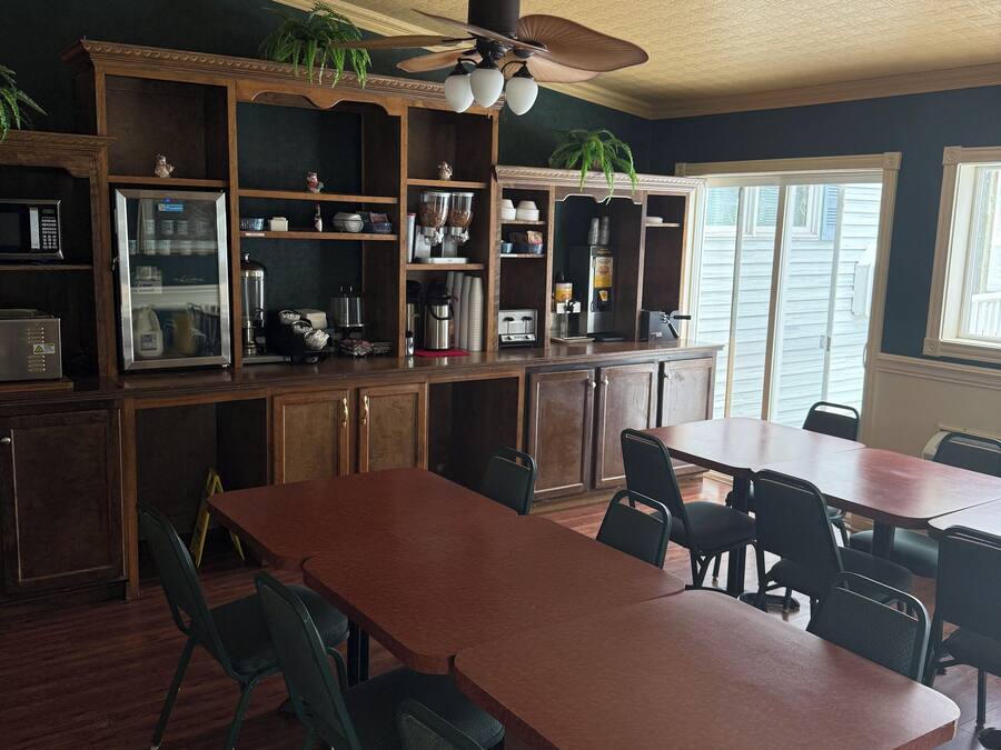 A spacious kitchen with wooden cabinets, a large dining table, and a ceiling fan.