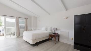 A bedroom with a bed, a nightstand, a lamp, a wardrobe, and a sliding glass door leading to an outdoor area.