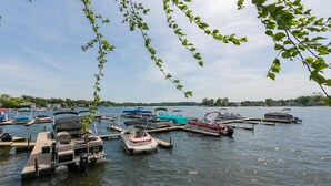 A marina with multiple boats docked, calm water, and a clear sky.