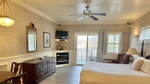 A spacious room with a large bed, a sitting area with a table and chairs, a fireplace, and a view through a sliding glass door.