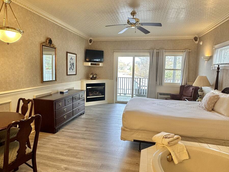 A spacious room with a large bed, a sitting area with a table and chairs, a fireplace, and a view through a sliding glass door.