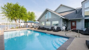 A swimming pool with lounge chairs and a covered area.