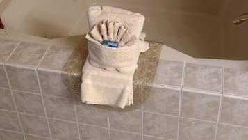 Un bagno con una vasca, pareti piastrellate e un portasciugamani con asciugni piegati.