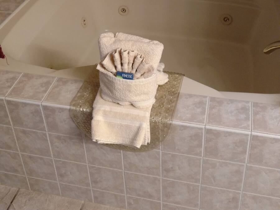 Un bagno con una vasca, pareti piastrellate e un portasciugamani con asciugni piegati.