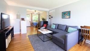 A living room with a grey sofa, a coffee table, a TV, and a wooden chair.
