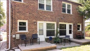 A brick building with a patio area featuring outdoor seating and a small table.