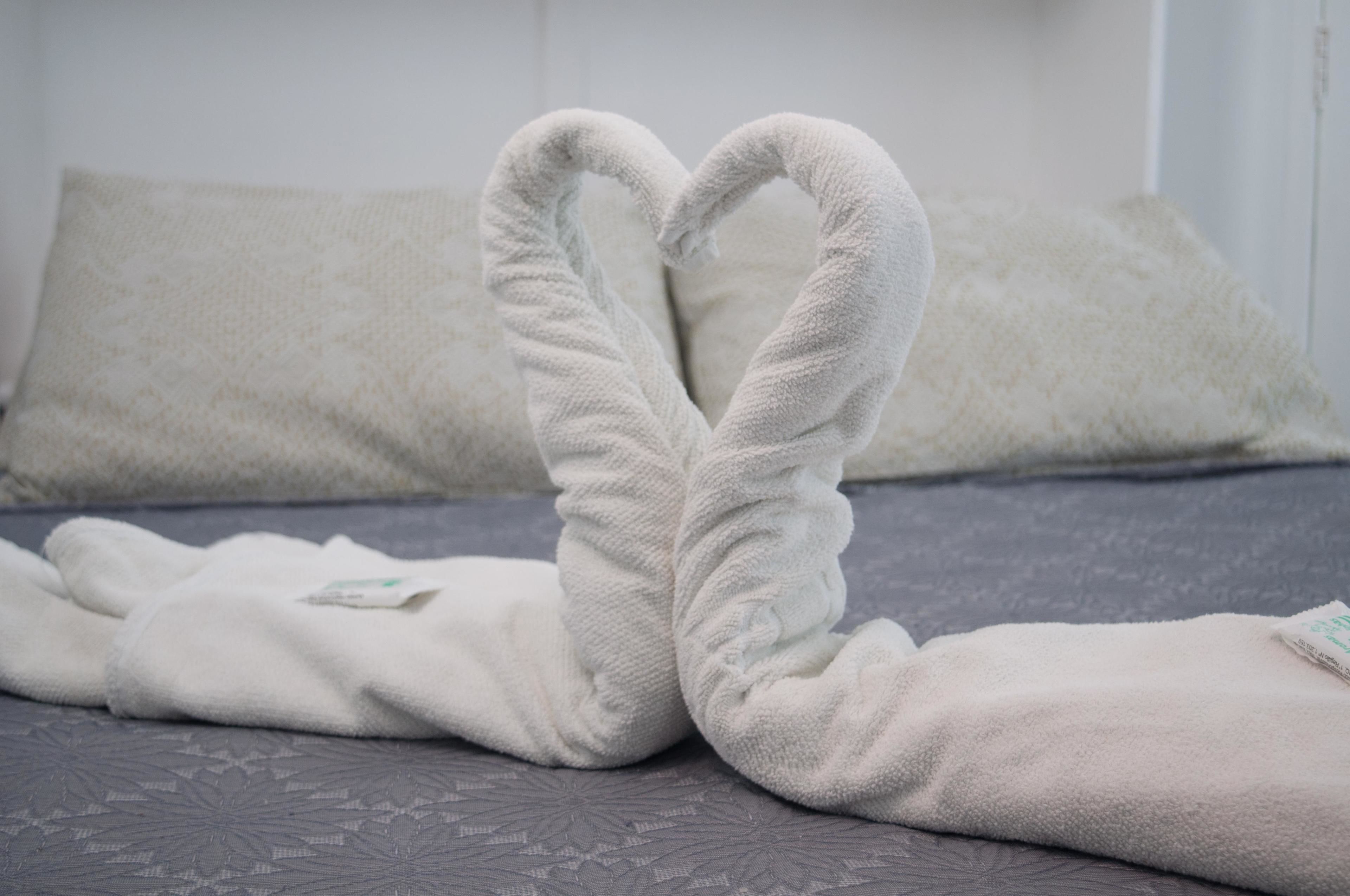 Una cama con una toalla dispuesta en forma de corazón.