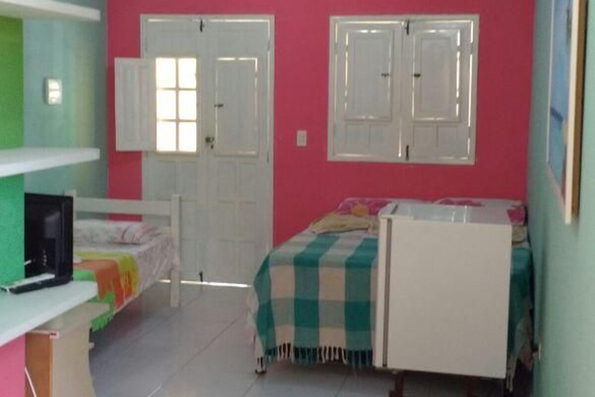 A bedroom with a bed, a desk, a chair, a wardrobe, and a window.