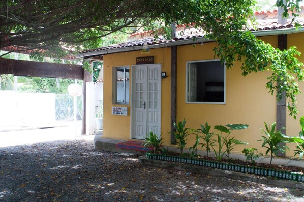 A yellow building with a reception area, a door, and a window. - Pousada Recanto Rubaiyat (Ipojuca)